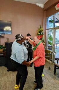 A resident and staff member dance together